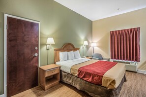 Une chambre d’hôtel avec un lit en bois, des tables de chevet, des lampes, une fenêtre avec des rideaux et une porte.