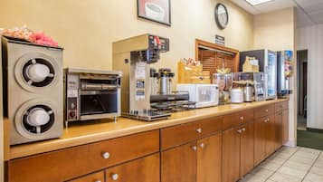 Un espace où l'on peut se servir soi-même pour le petit-déjeuner, avec des machines à café, un four à micro-ondes et une variété d'aliments.