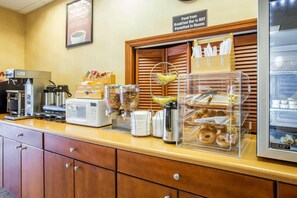 A breakfast bar with a coffee machine, microwave, cereal dispenser, and a display case with pastries. - Econo Lodge Valdosta (Valdosta)