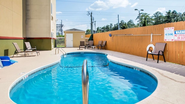 Une piscine avec des chaises longues et une clôture en bois.