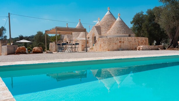 A swimming pool with stone buildings in the background. - Trulli Scacciapensieri con Piscina (Ceglie Messapica)