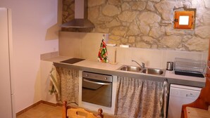 A compact kitchen with a stone wall, a built-in oven, a sink, and a small window. - Detached rural 19th century country house. (Calonge de Segarra)