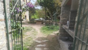 A narrow pathway leading to a rustic stone building with a metal gate on the left. - Detached rural 19th century country house. (Calonge de Segarra)