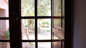 A view through a window with a wooden frame, leading to an outdoor area with trees and a bench. - Detached rural 19th century country house. (Calonge de Segarra)