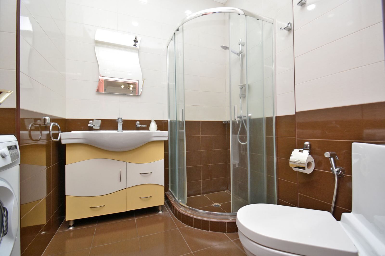 Ein modernes Badezimmer mit einer Duschkabine, einem Waschbecken mit Spiegel und einer Toilette.
