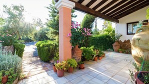 Un patio cubierto con suelo de baldosas, plantas en macetas y una estructura de pérgola.