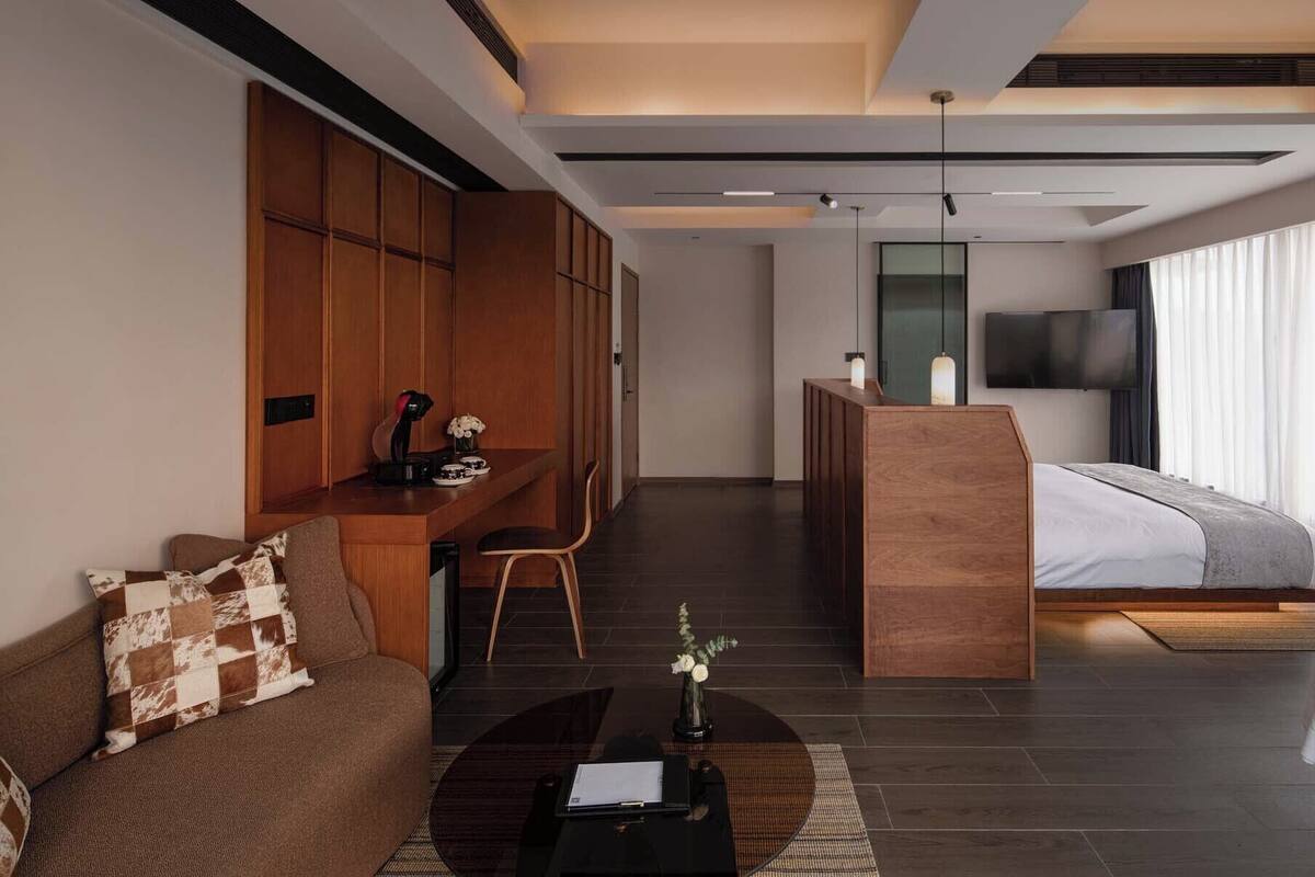 Una habitación de hotel moderna con cama, escritorio, sofá y televisión.