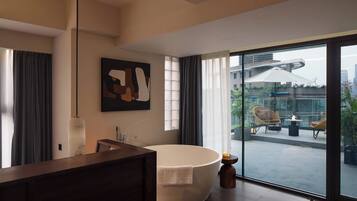 A modern bathroom with a freestanding bathtub, a large mirror, and a contemporary artwork on the wall.