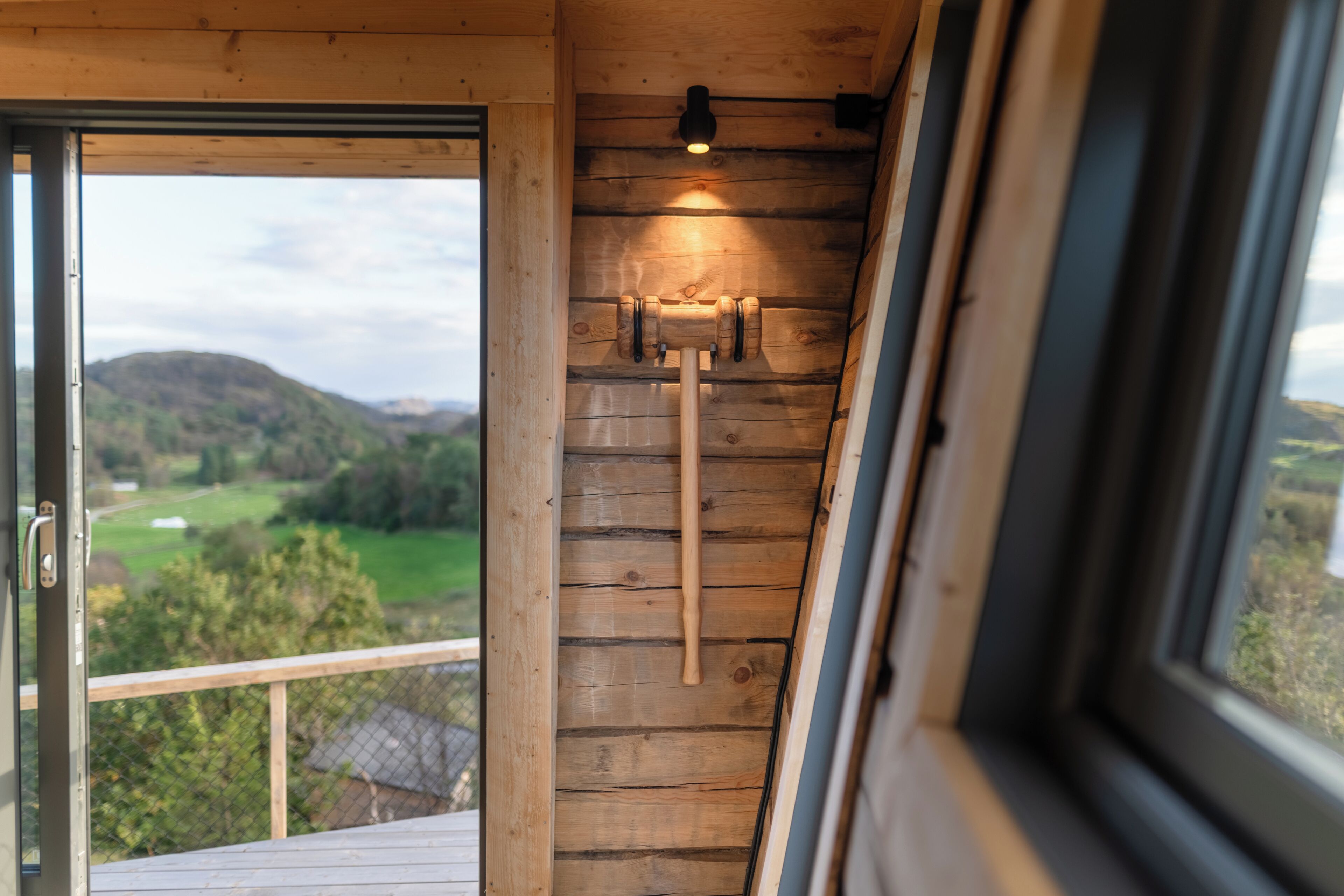 Interior de madera con ventana que da a un paisaje verde.