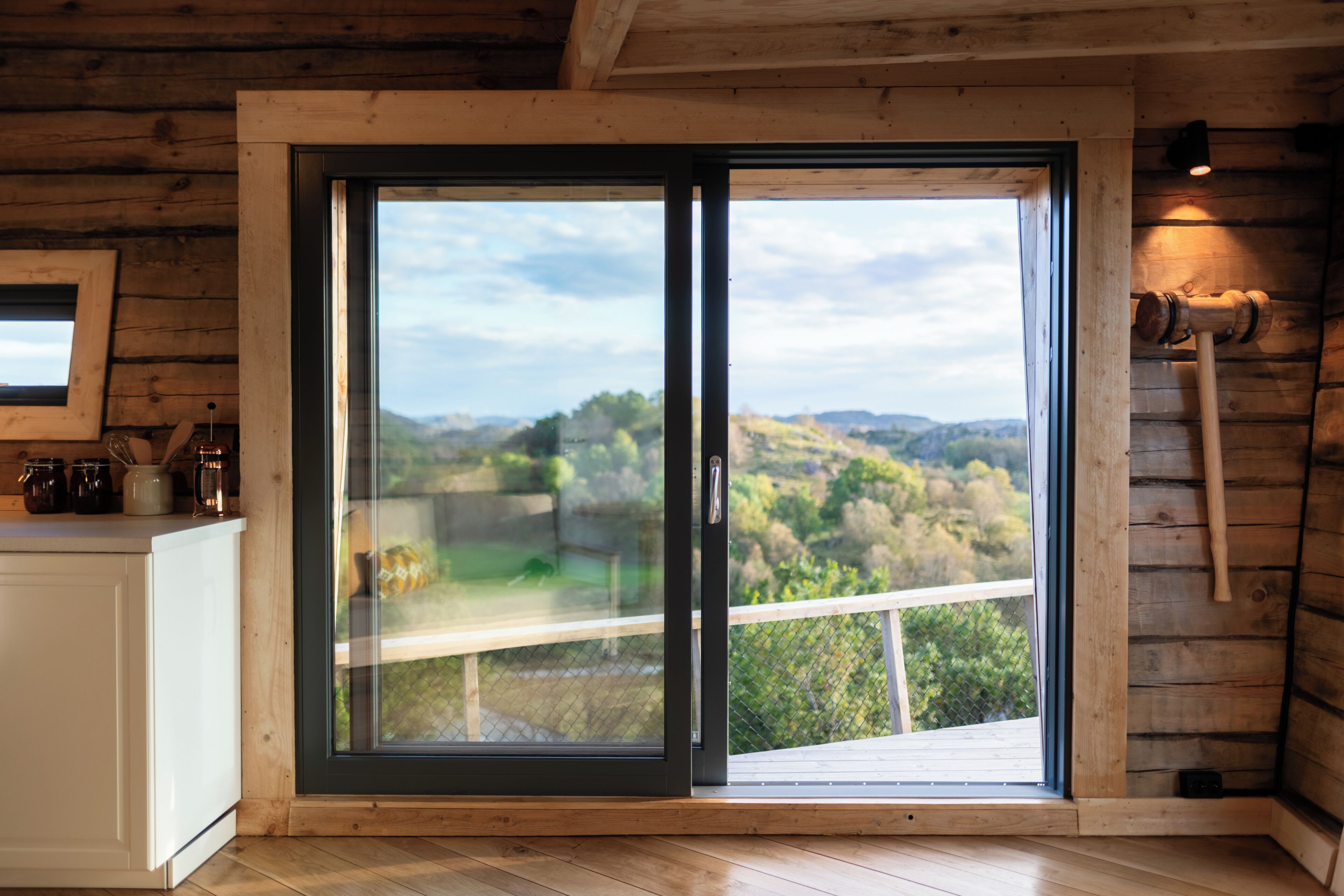 A wooden cabin interior with a large sliding glass door leading to a balcony.