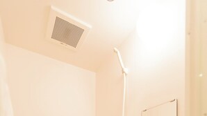 A bathroom with a bathtub, a shower, and a shelf with toiletries. - b&Imazato (Osaka)
