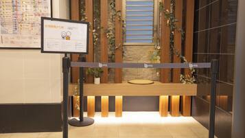 A reception desk with a sign, wooden paneling, and a potted plant.