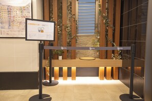 A reception desk with a sign, wooden paneling, and a potted plant. - b&Imazato (Osaka)