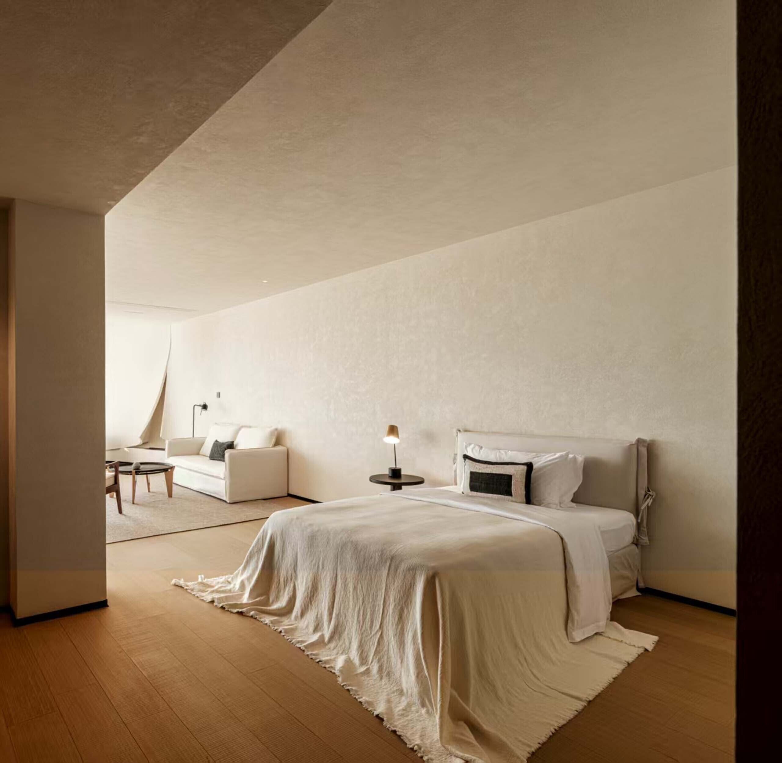A modern bedroom with a large bed, a small desk, and a chair.