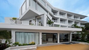 Ein modernes, mehrgeschossiges Hotel mit flachem Dach, großen Fenstern und einem Balkon mit weißer Brüstung.