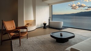 Ein modernes Badezimmer mit einer Badewanne, einem Sessel und Meerblick.