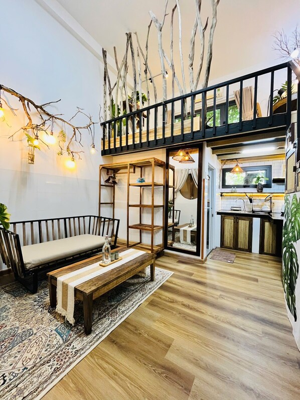Un espacio habitable moderno estilo loft con cama elevadasofa, una mesita de centro y una zona de cocina.
