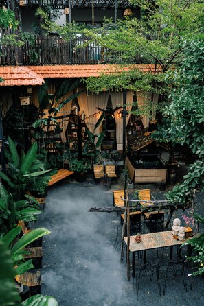 A courtyard with a wooden table and chairs, surrounded by lush greenery and a tiled roof structure. - TINH Retreat Phu Quoc (Phu Quoc)
