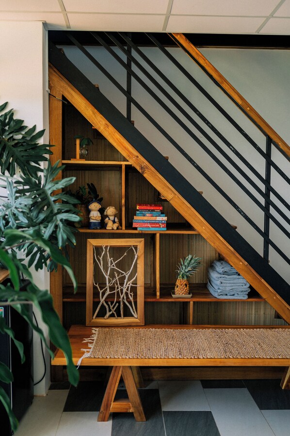 Un escalier avec une rampe en bois et des marches noires, menant à un niveau inférieur.