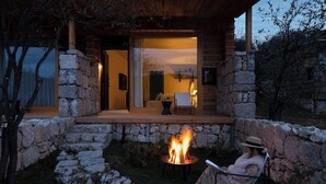 A stone-walled outdoor area with a fire pit and a person relaxing in a chair. - Shangri-La Bandu Xingye Muge Manor Hotel (Deqin)