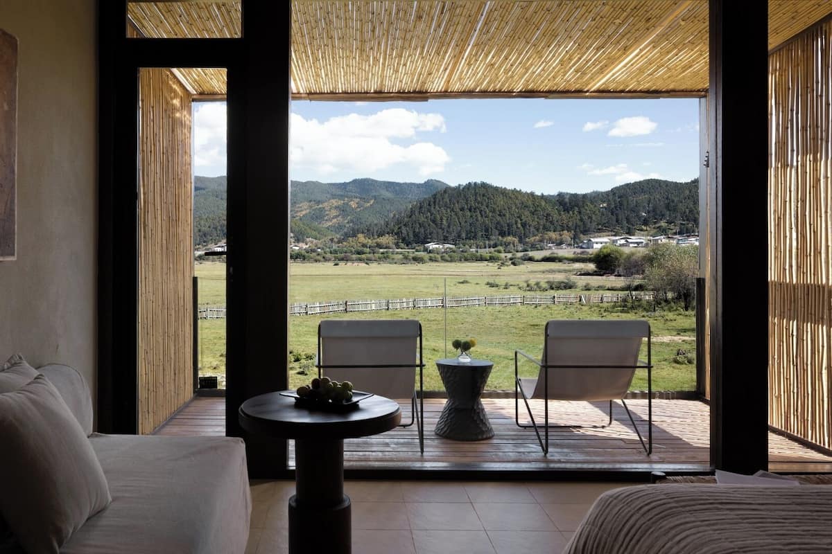 Una habitación con un ventanal amplio, un sofá, dos sillones y una mesita.
