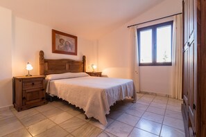 A bedroom with a wooden bed, two bedside tables with lamps, a window with curtains, and a painting on the wall. - Countryside Ibipozo Retreat in Pozo Alcón (Pozo Alcón)