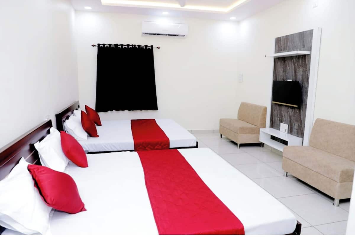 Une chambre d’hôtel avec deux lits, un canapé et une télévision.