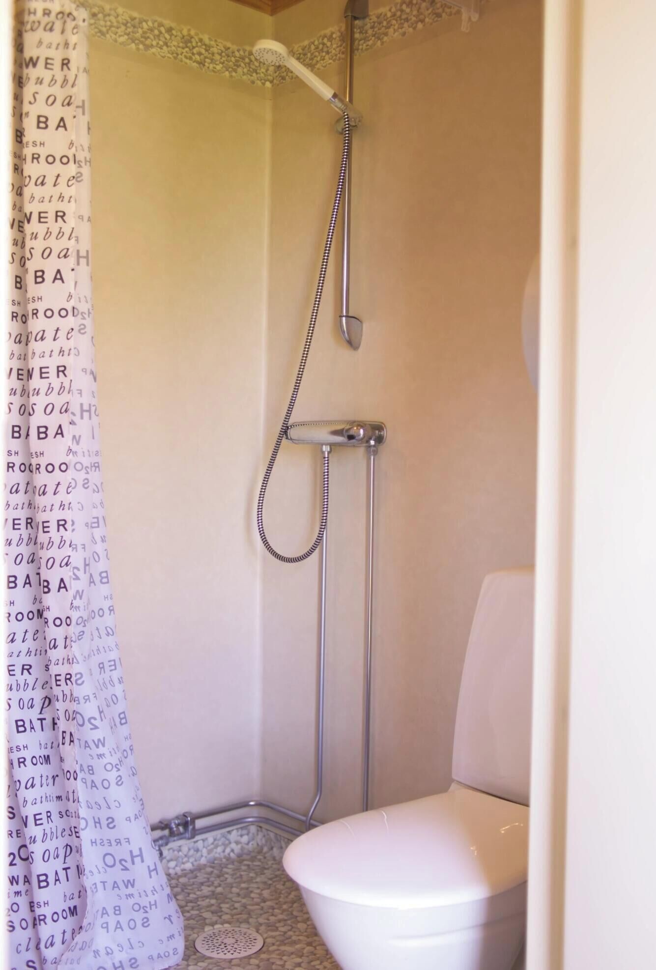 Un baño pequeño y funcional con ducha, inodoro y cortina de ducha estampada.