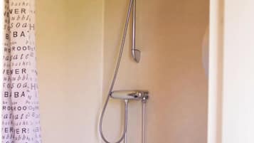 Un baño pequeño y funcional con ducha, inodoro y cortina de ducha estampada.