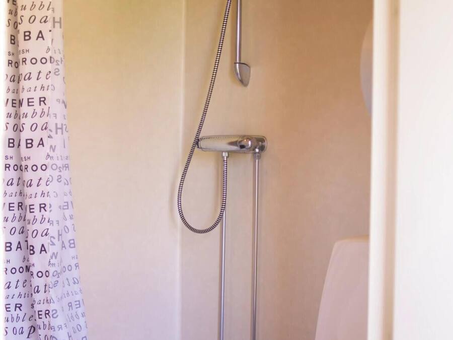 Un baño pequeño y funcional con ducha, inodoro y cortina de ducha estampada.
