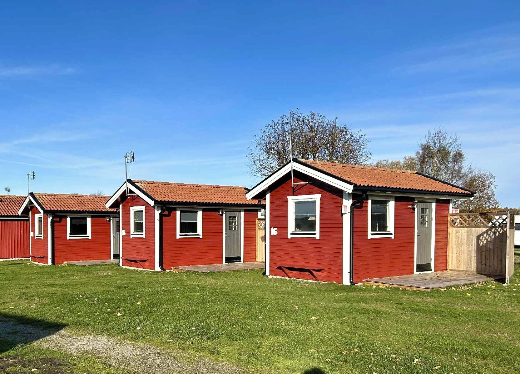 Una hilera de casas móviles rojas con detalles blancos, cada una con un pequeño porche y una ventana.