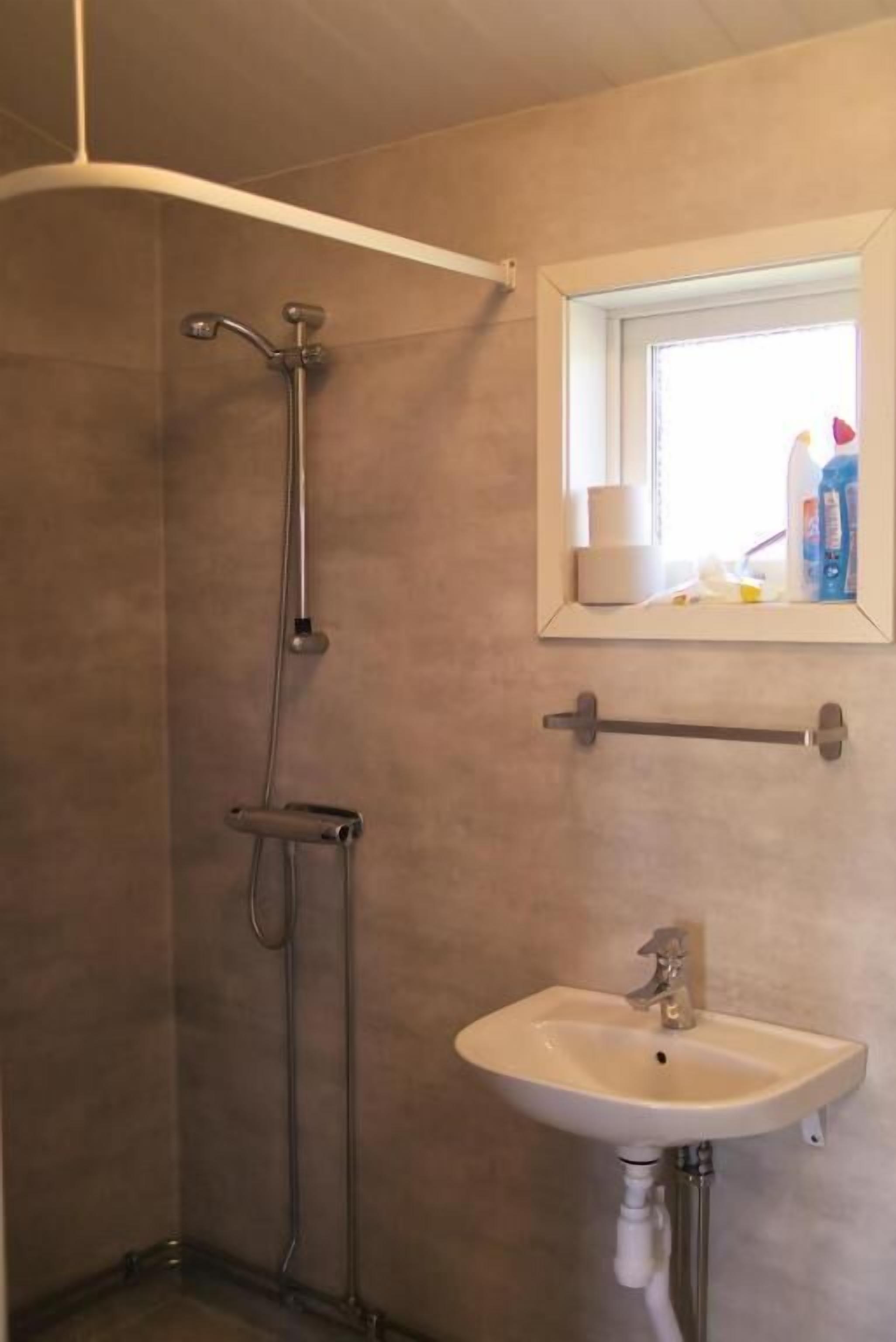Un baño con ducha, lavamanos y espejo.
