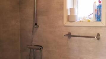 Un baño con ducha, lavamanos y espejo.