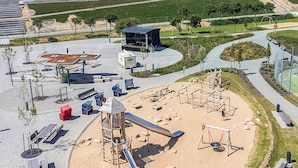 A playground with slides and swings, a covered seating area, and a sandy play zone. - 4 Star Holiday Home in Friedrichkoog (Friedrichskoog)
