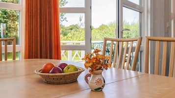 Una mesa de comedor con un frutero y un jarrón de flores.