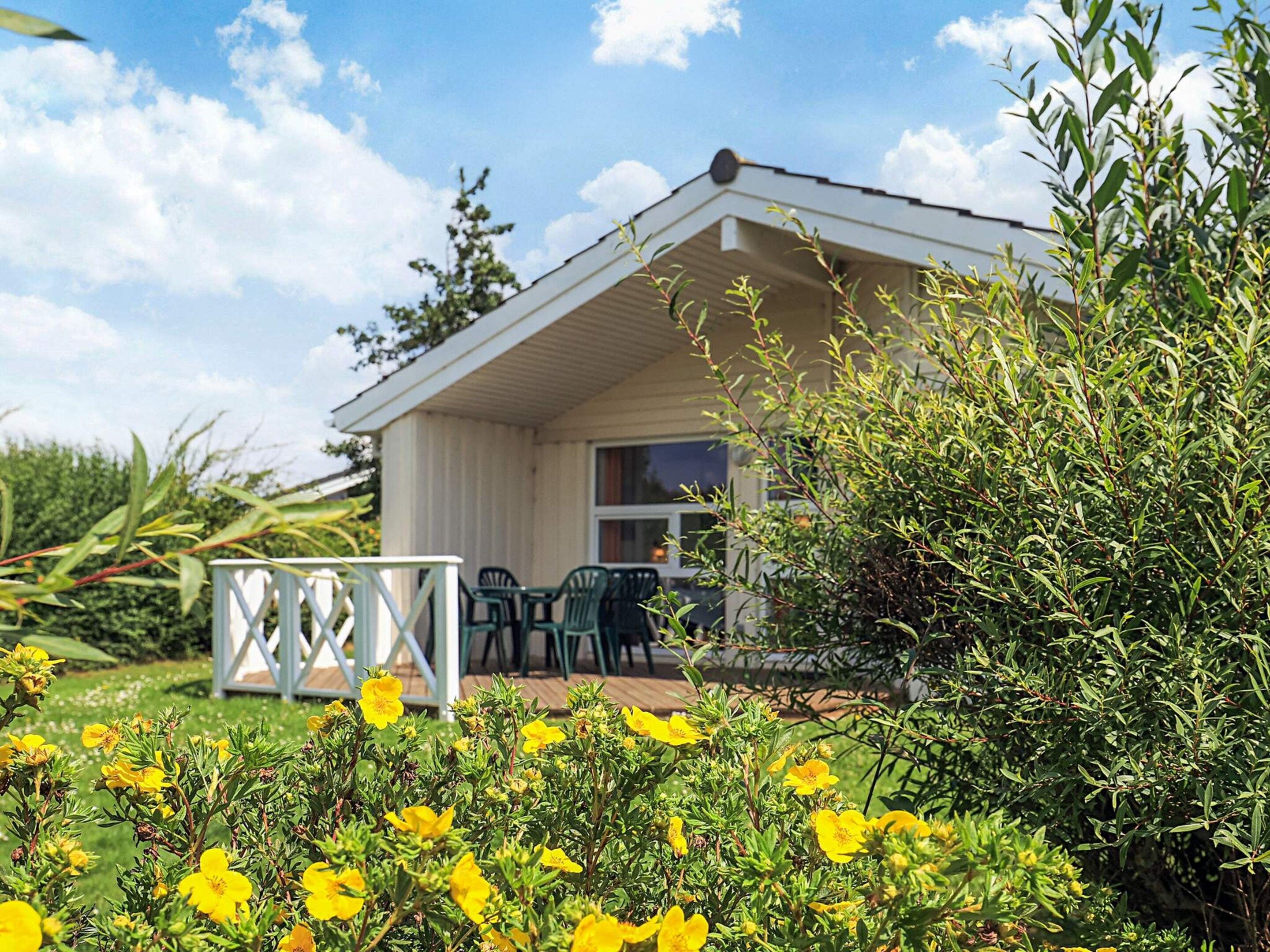 A single-story building with a covered patio area, a small table, and chairs.