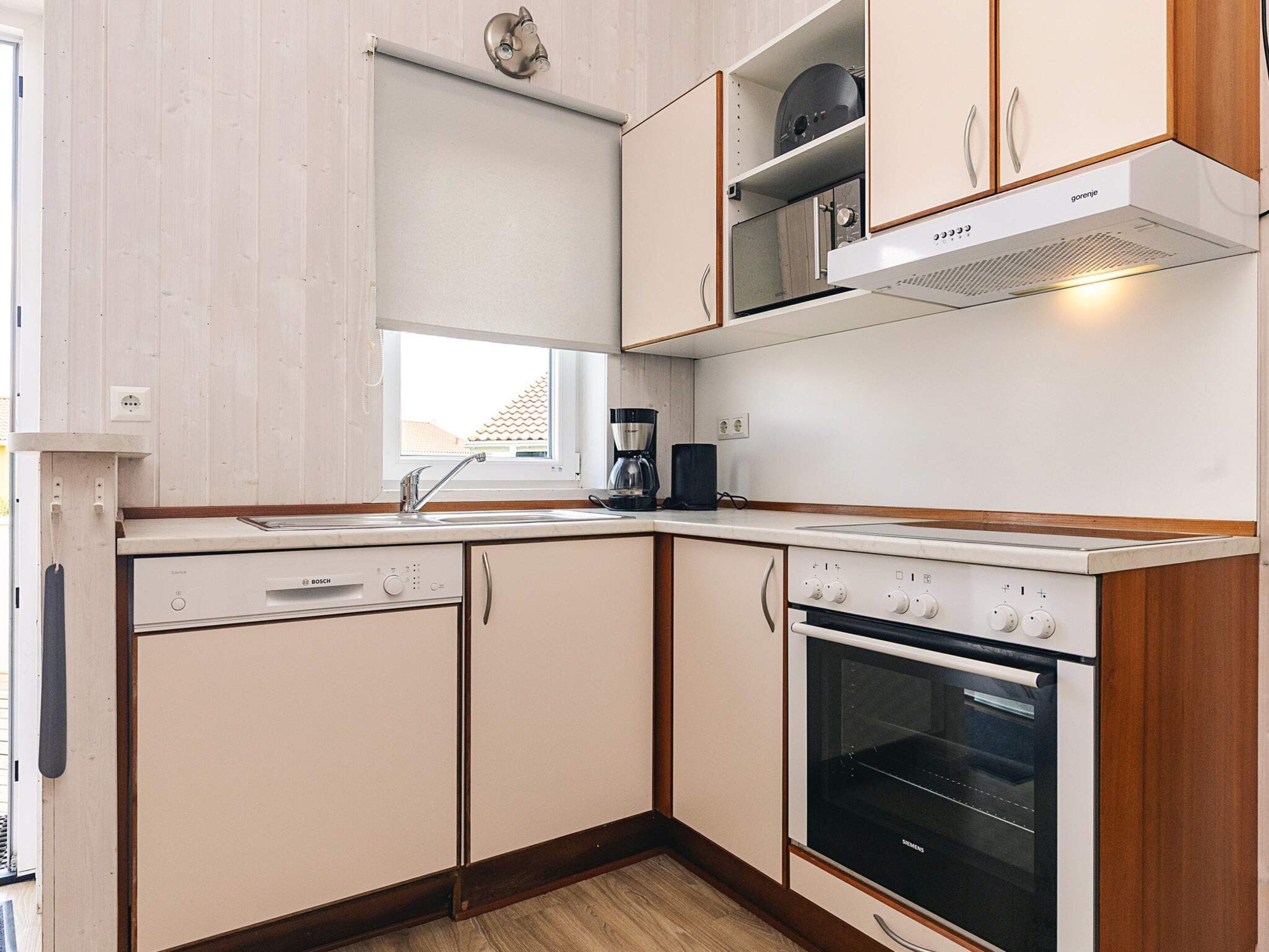 Una cocina con lavavajillas Bosch, horno Siemens y cafetera en la encimera.