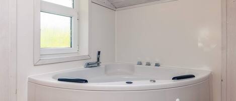 A white bathtub in a room with white walls and a window.