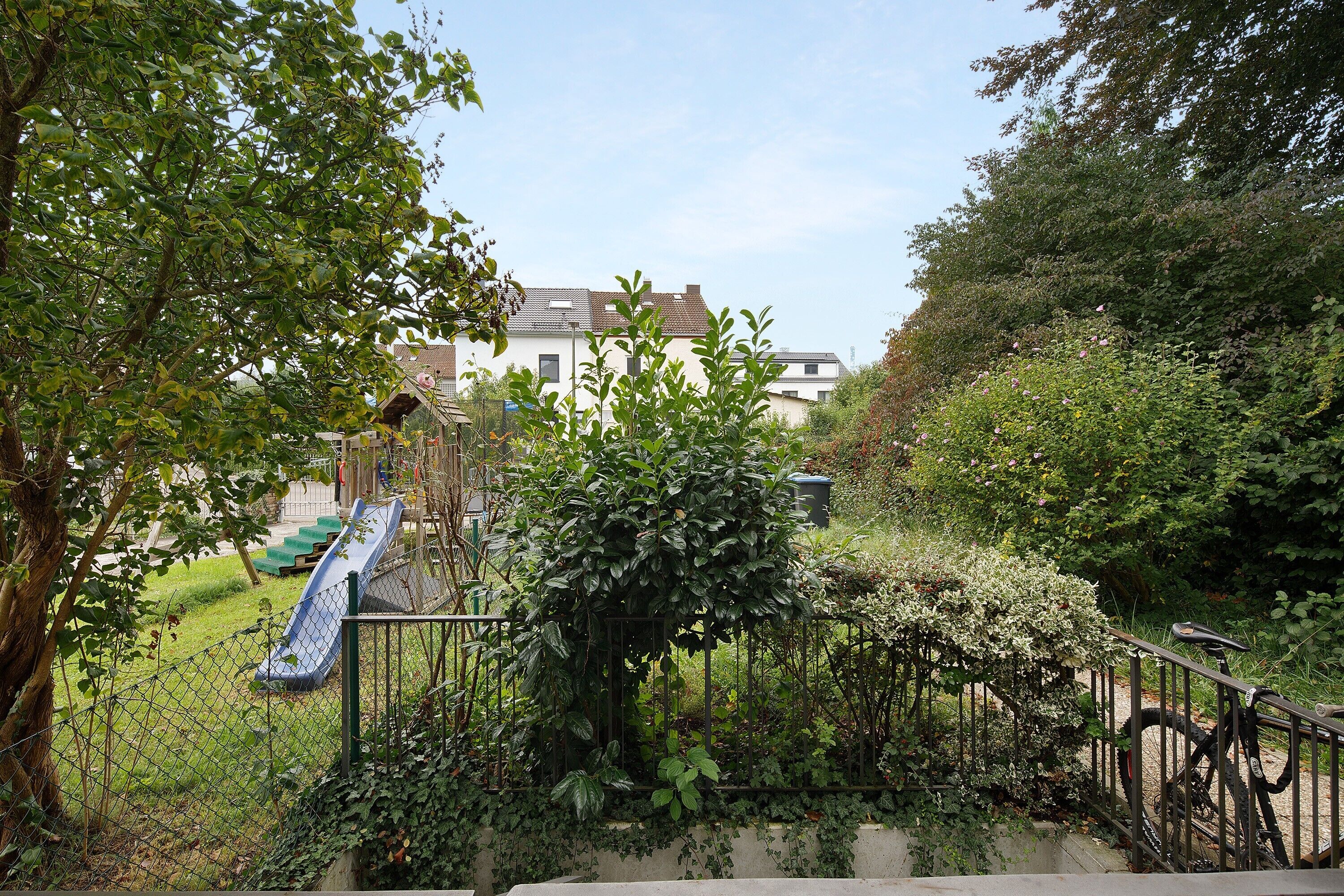 Ein Wohngebiet mit einem Spielplatz, einem Fahrrad und einem Haus im Hintergrund.
