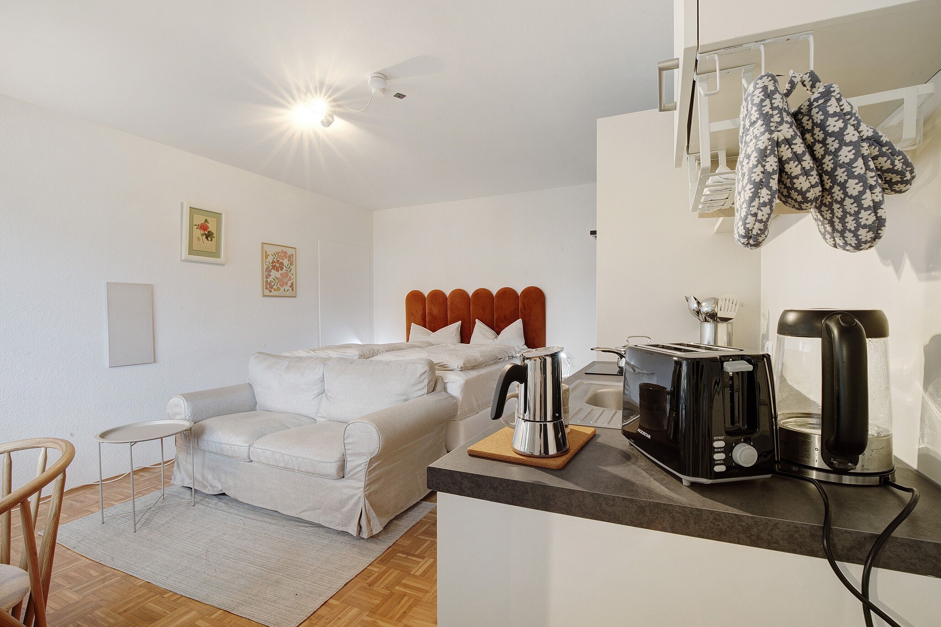 A modern room with a bed, a small table, a coffee maker, and a toaster.