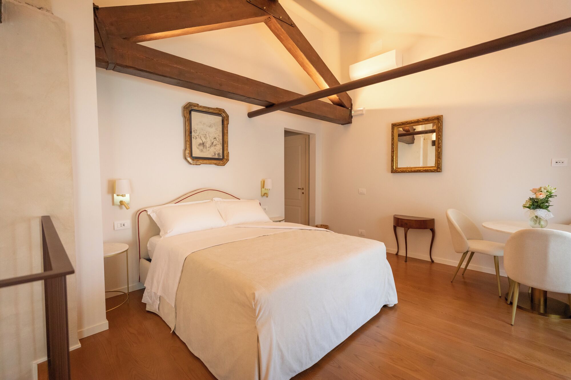 A bedroom with a bed, bedside tables, a desk, a chair, and a mirror.