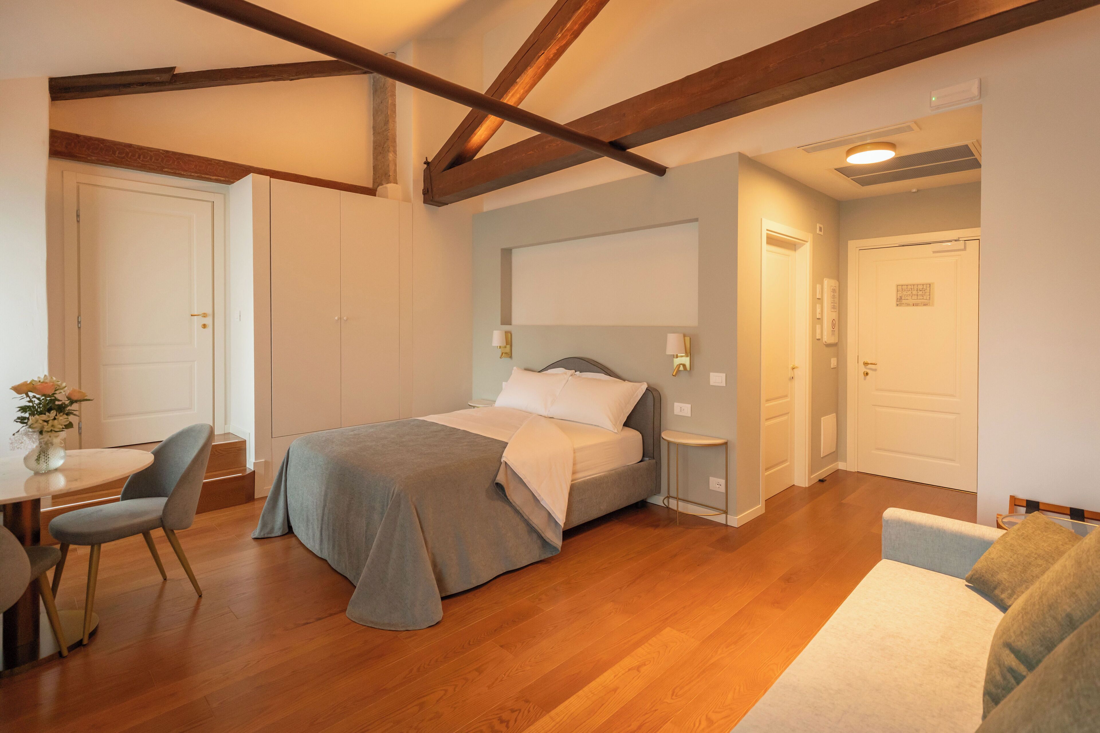 A bedroom with a bed, bedside tables, a chair, and a small table with a vase.