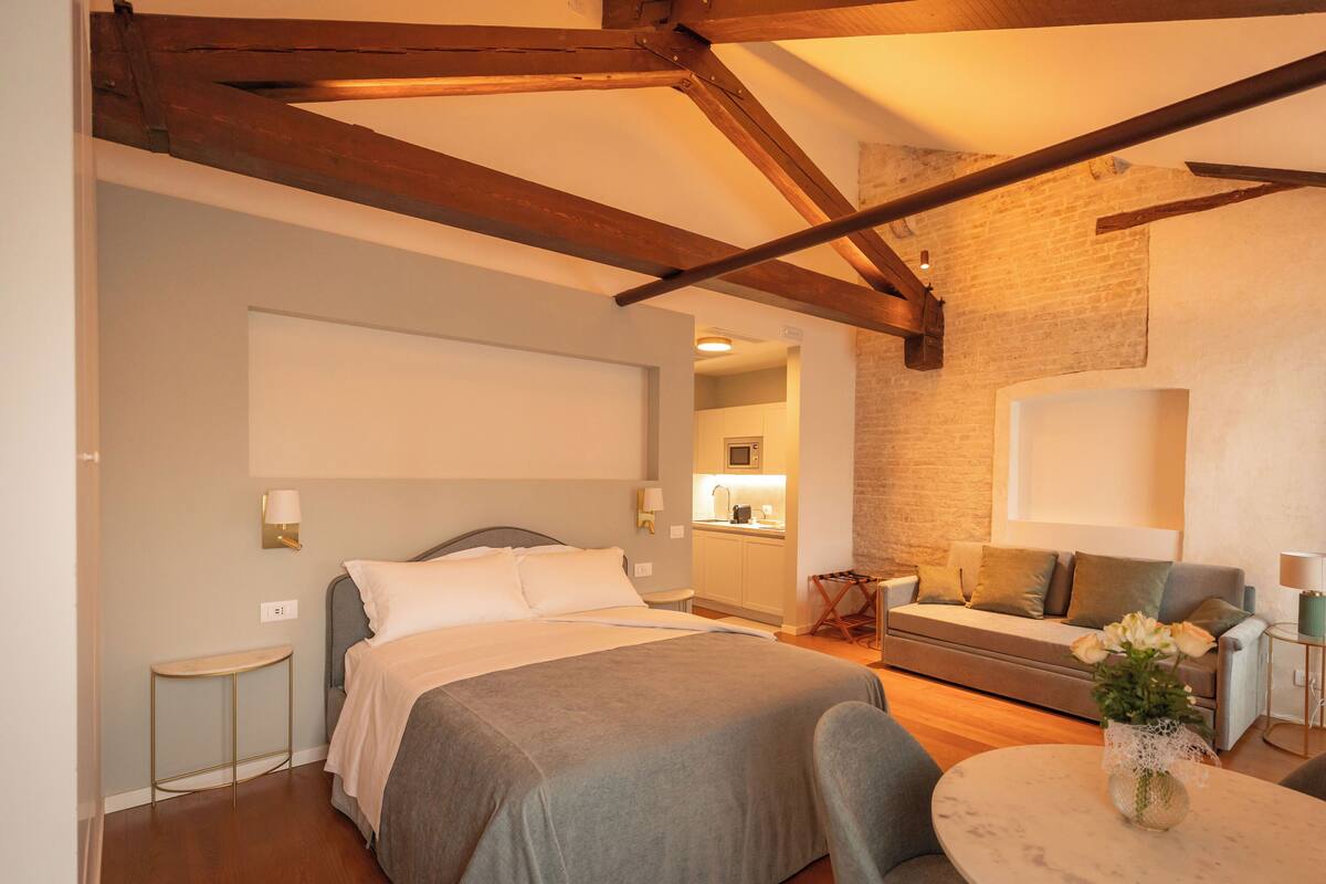 A bedroom with a bed, bedside table, and a small round table with a vase.