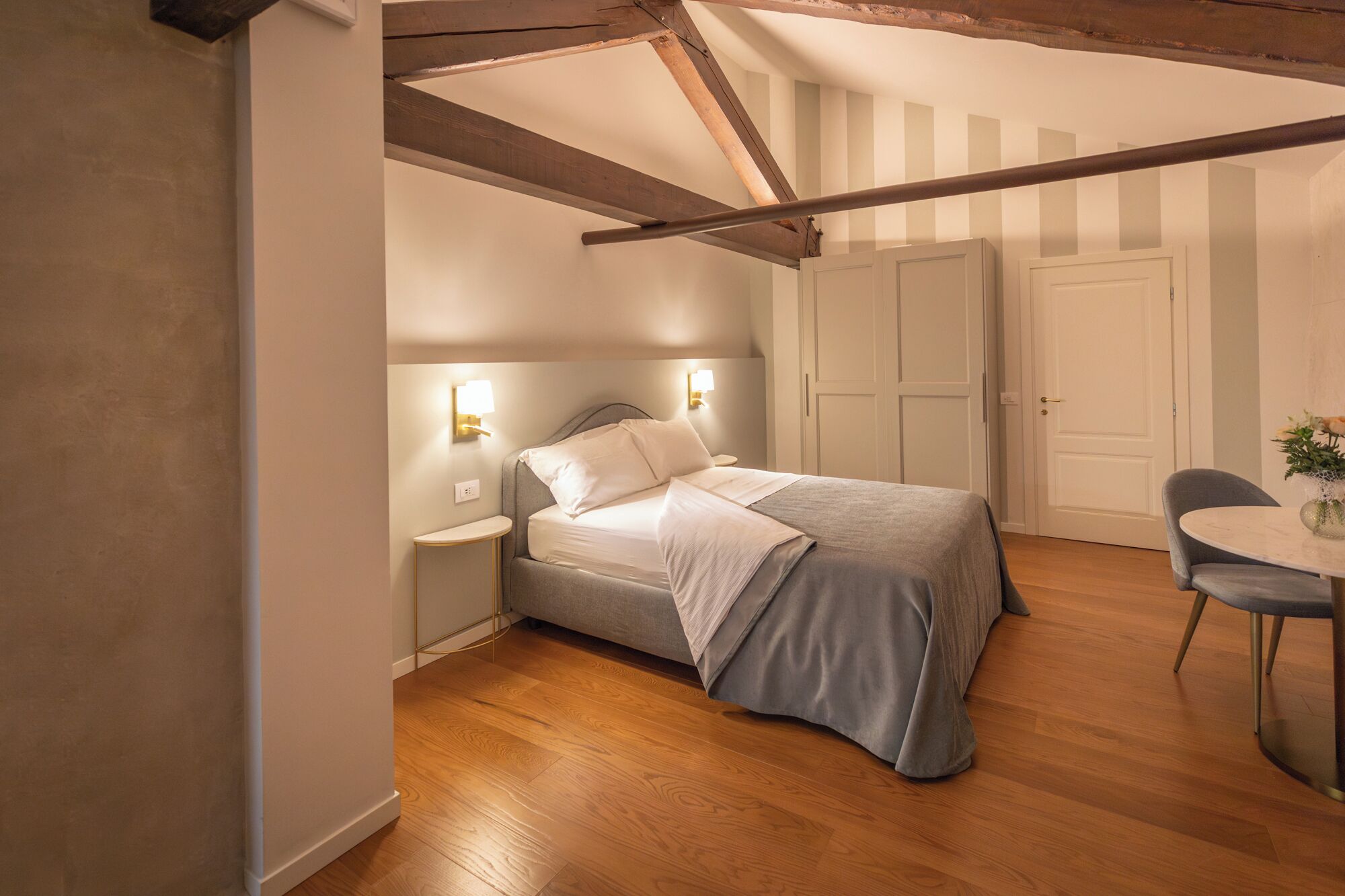 Un dormitorio con cama, mesitas de noche, una silla y una puerta.