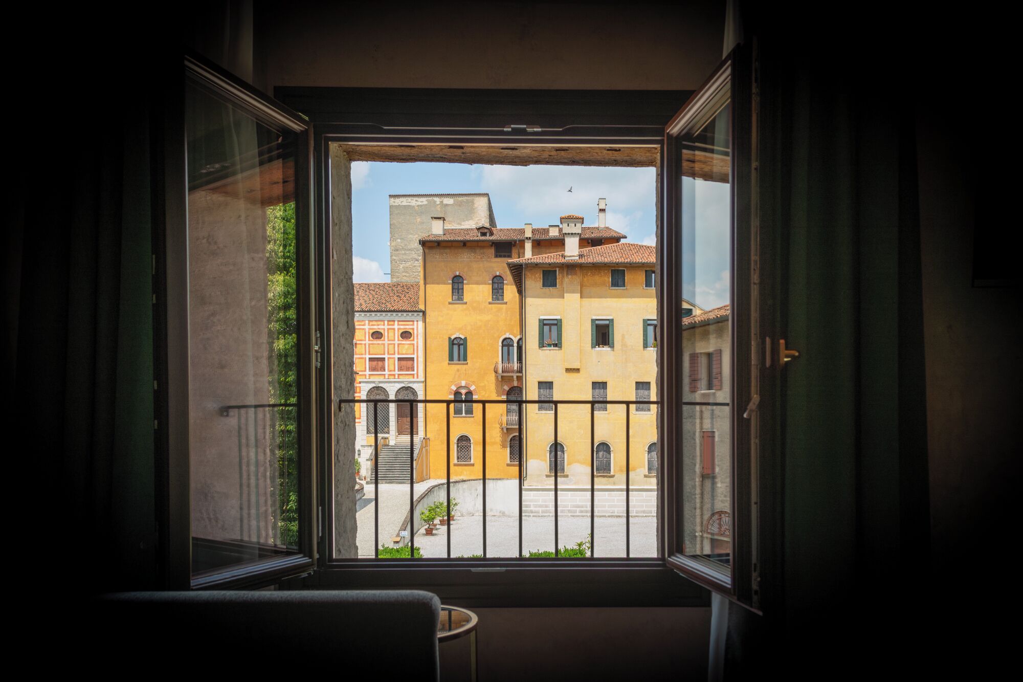 Vista desde una ventana con balcón, con vista a una calle con edificios.