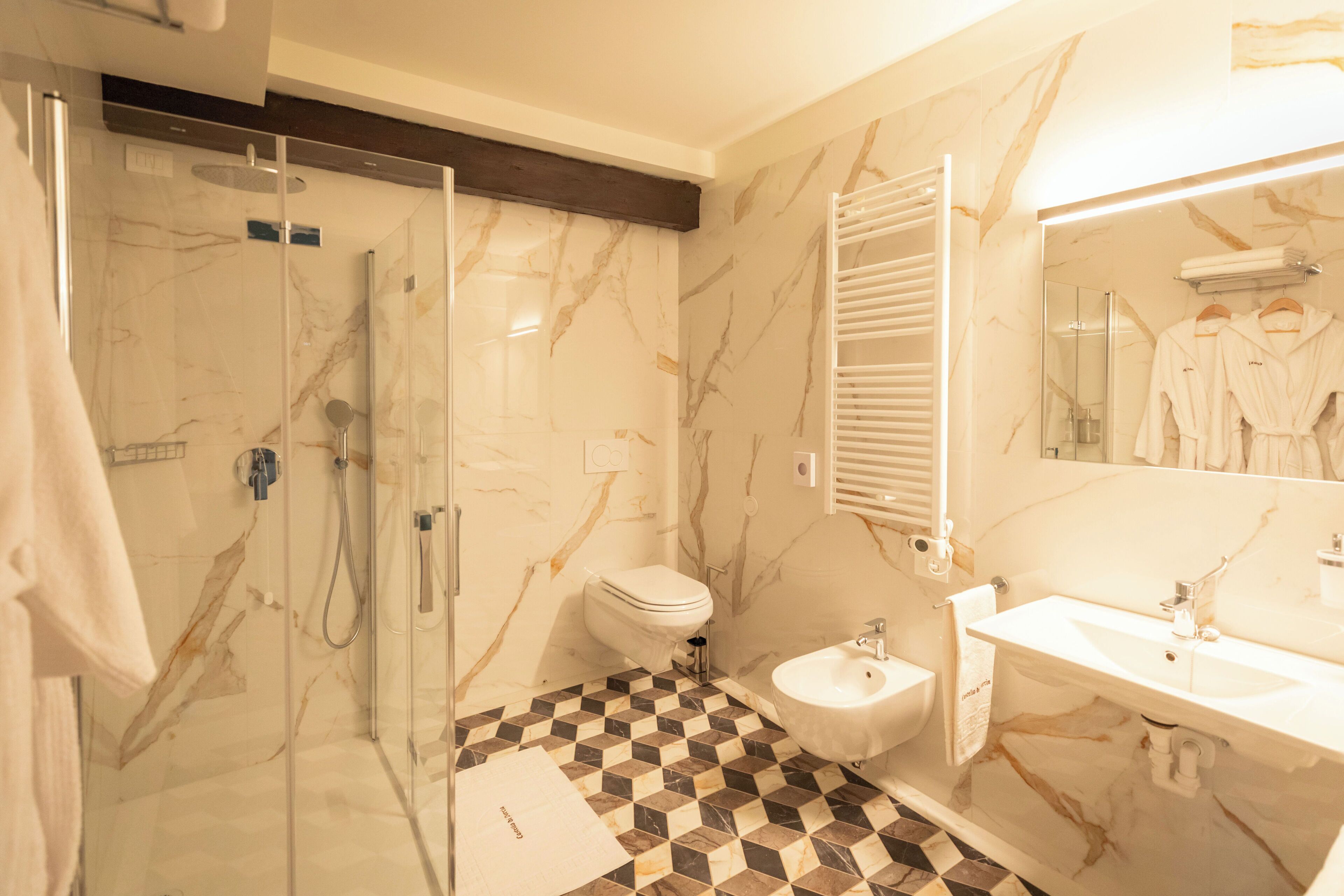 Une salle de bain avec une douche à parois de verre, des toilettes, un bidet et un lavabo avec un miroir.