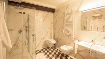 Une salle de bain avec une douche à parois de verre, des toilettes, un bidet et un lavabo avec un miroir.