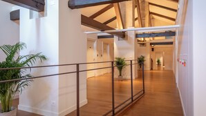 Un interior espacioso con techos altos, vigas de madera a la vista y un largo pasillo que conduce a varias habitaciones.