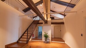Un interior amplio con una escalera de madera, una planta en maceta y una puerta con el número 7.
