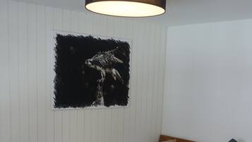 Un lit bien fait, avec un cadre en bois, une tête de lit et une table de chevet sur laquelle se trouvent une lampe et deux bouteilles.
